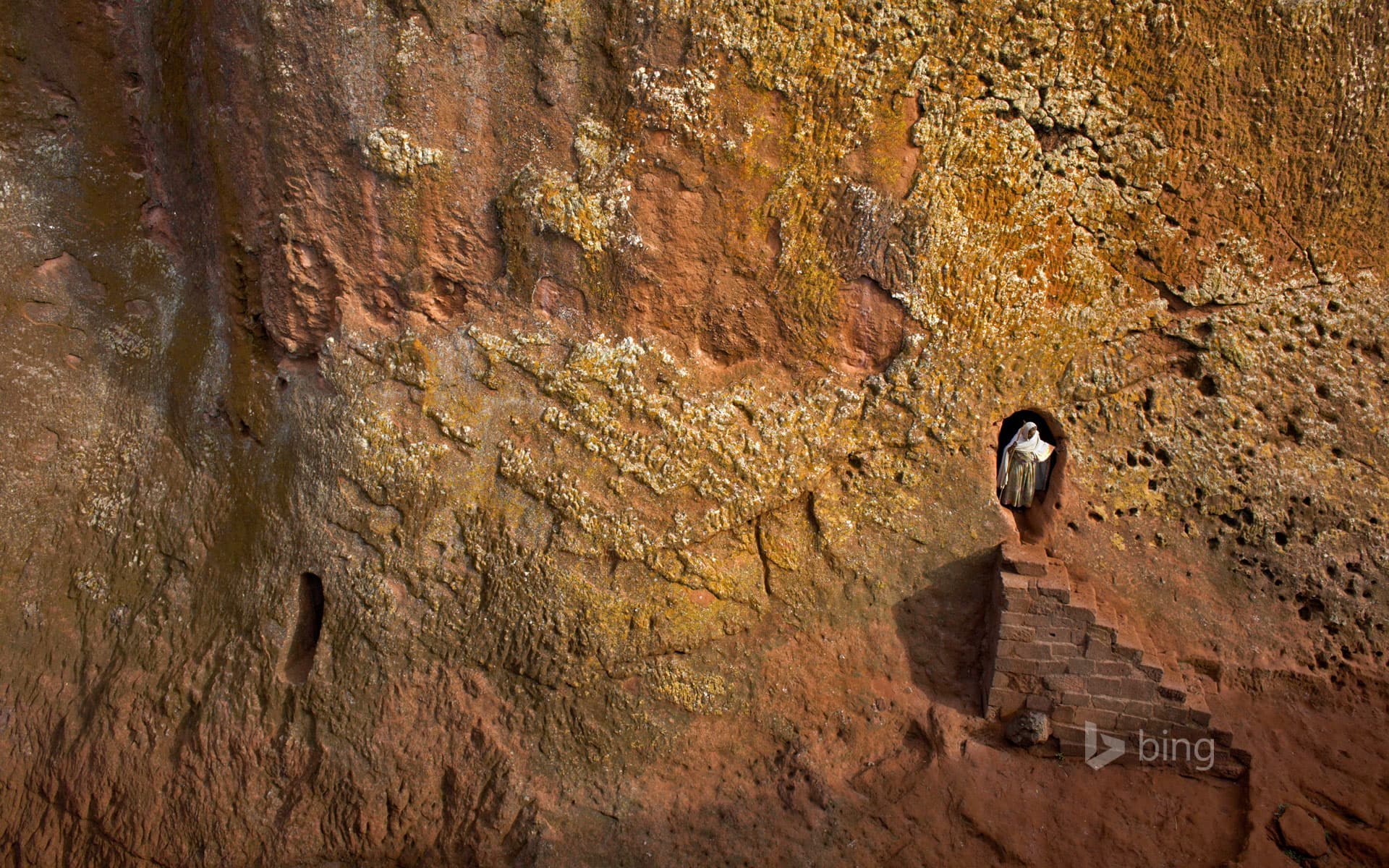 Bing Wallpaper: Woman emerges from a tunnel leading to Bet Amanuel, in Lalibela, Ethiopia