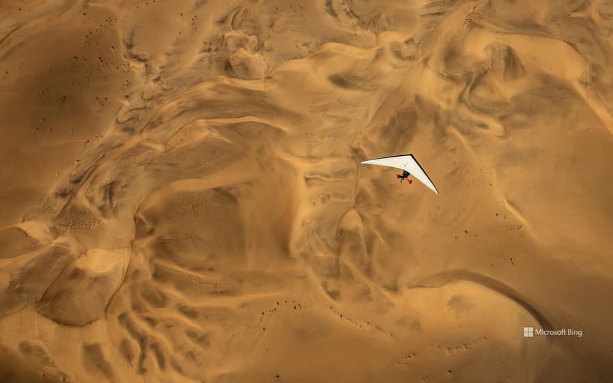 An ultralight aircraft flying over the sands of Namibia