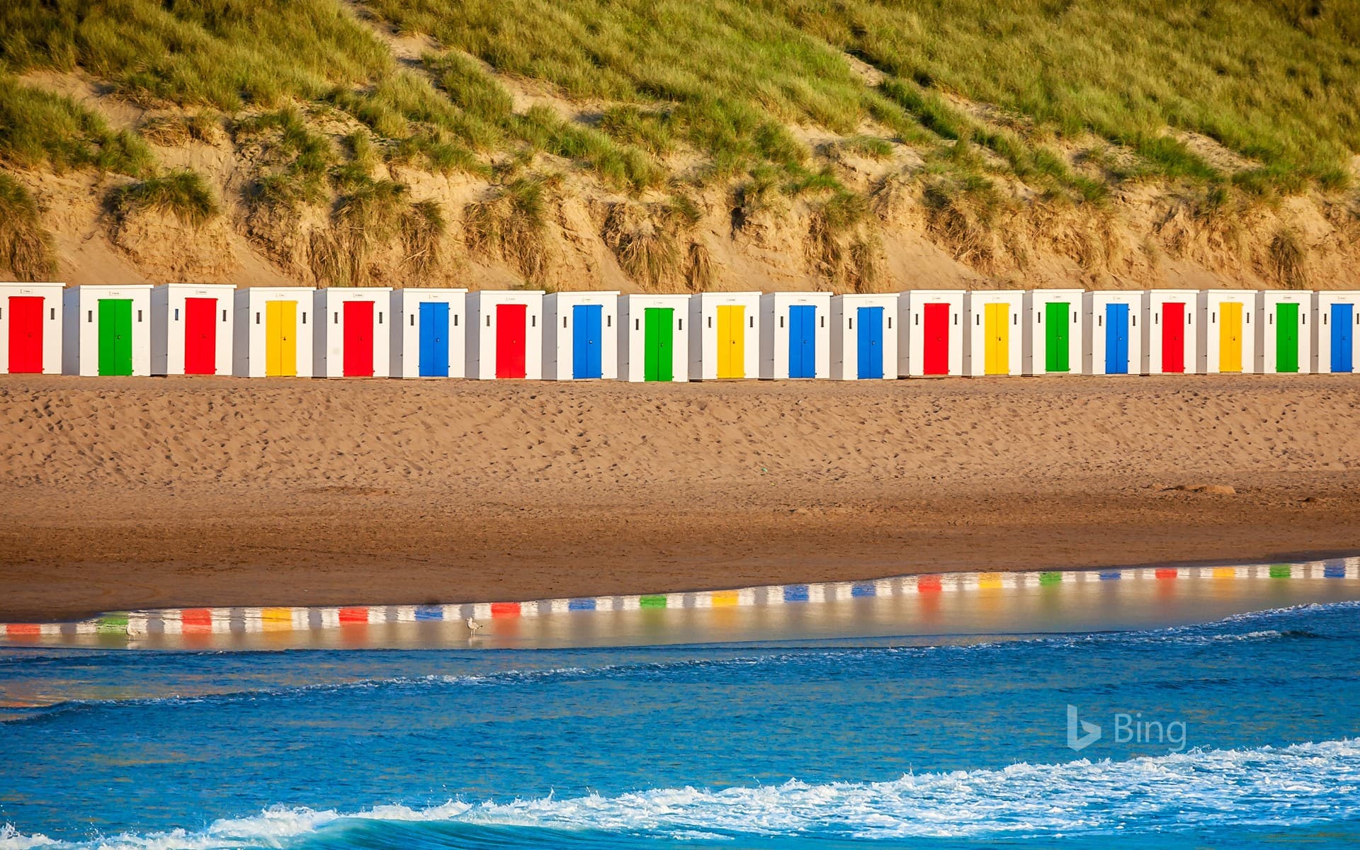 Bing Wallpaper: Beach huts reflecting in the water at Woolacombe Beach, Devon